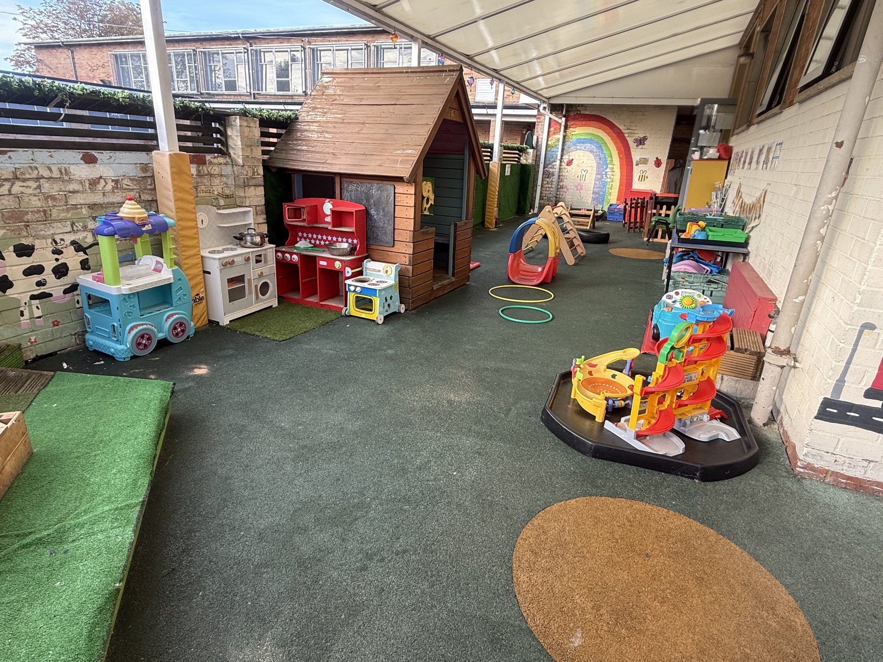 Baby room covered outdoor play area with a wooden play house and role-play kitchens