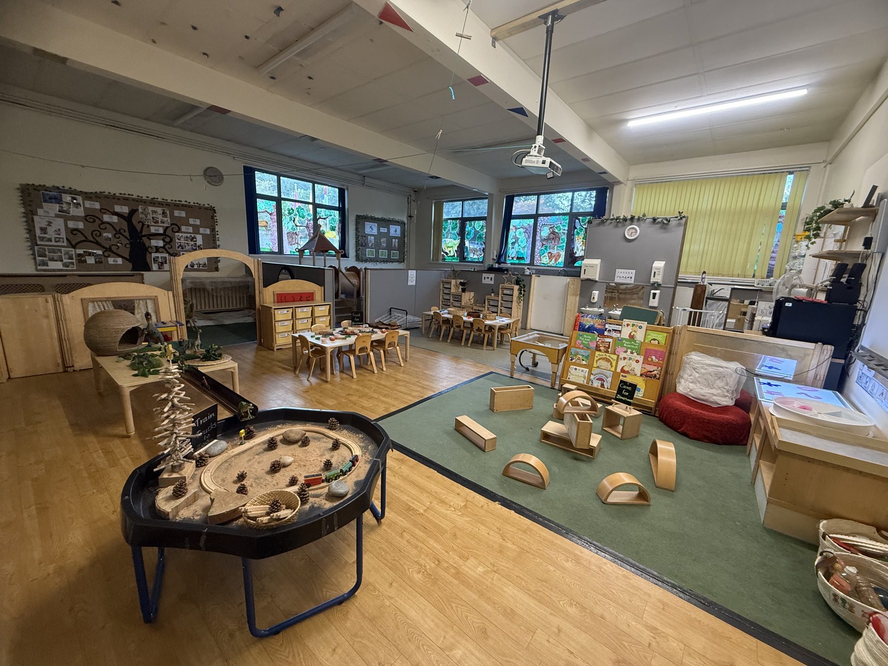 Inside the toddler room: a tuff tray, wooden blocks, book corner and small tables