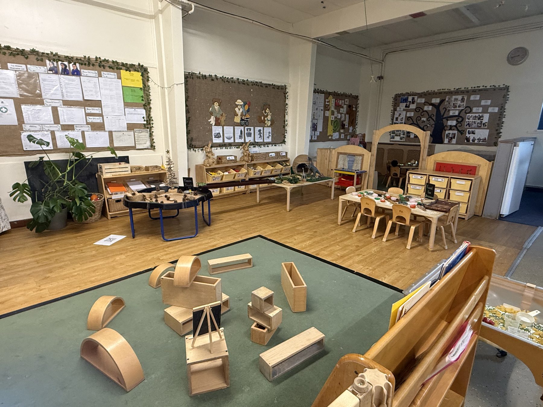 Toddler room play area with wooden blocks, tables and chairs and learning displays